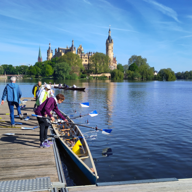 Ruderboot an einem Steg mit dem Schloss Schwerin im Hintergrund