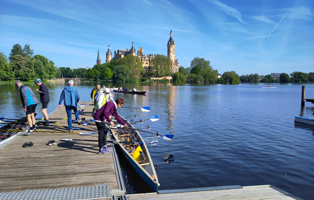 Ruderboot an einem Steg mit dem Schloss Schwerin im Hintergrund